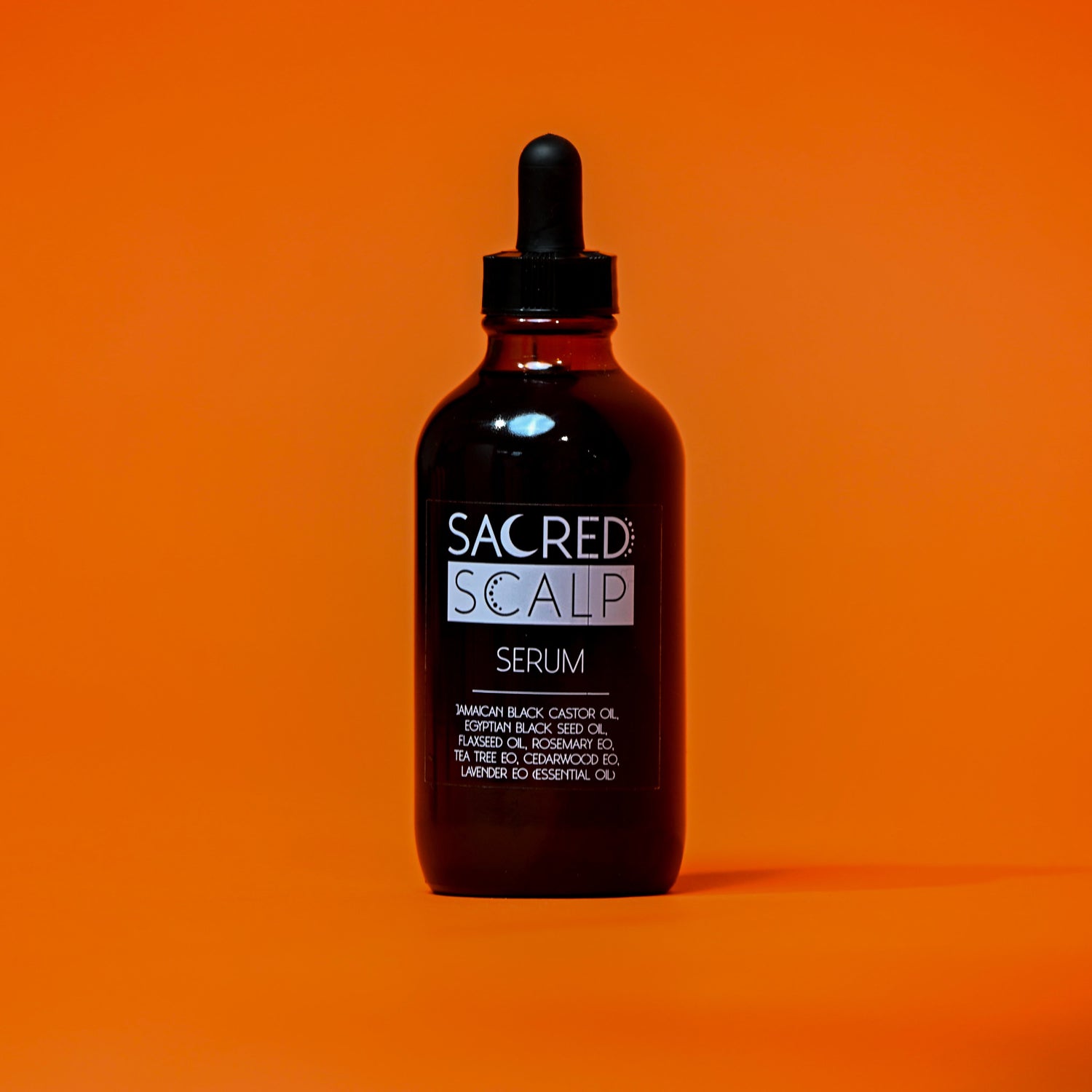 Bottle of Sacred Scalp Serum on an orange background